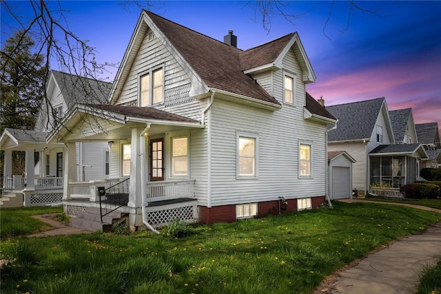 property exterior at dusk featuring a garage, covered porch, an outdoor structure, and a lawn