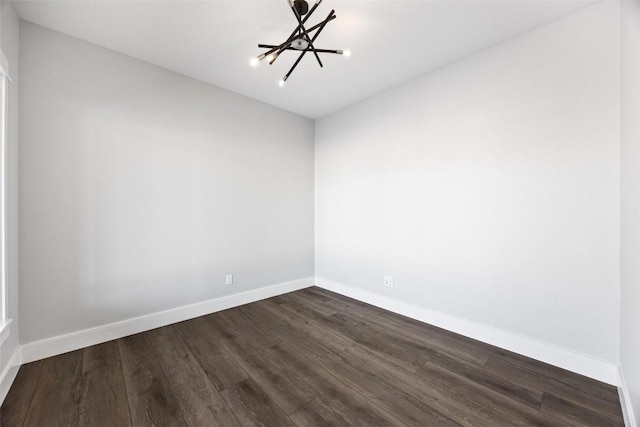 spare room with dark hardwood / wood-style flooring and an inviting chandelier