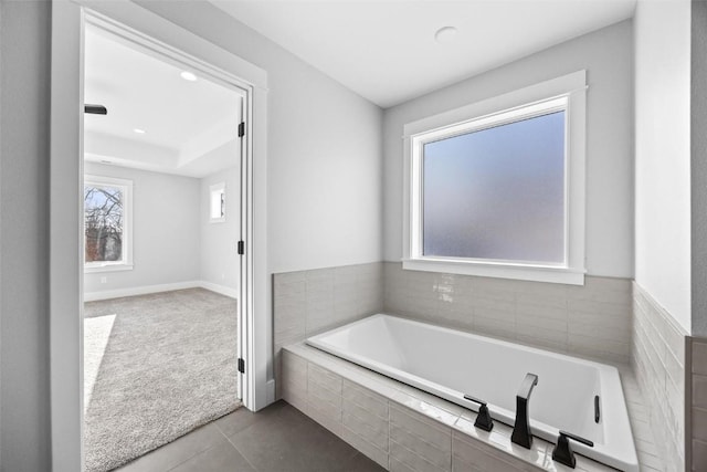 bathroom featuring a relaxing tiled tub and tile patterned flooring