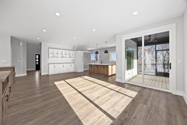 unfurnished living room featuring ceiling fan, dark hardwood / wood-style flooring, and sink