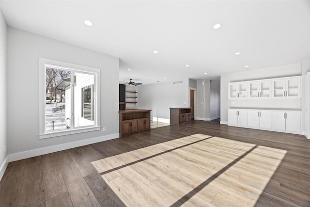 unfurnished living room with ceiling fan and dark wood-type flooring