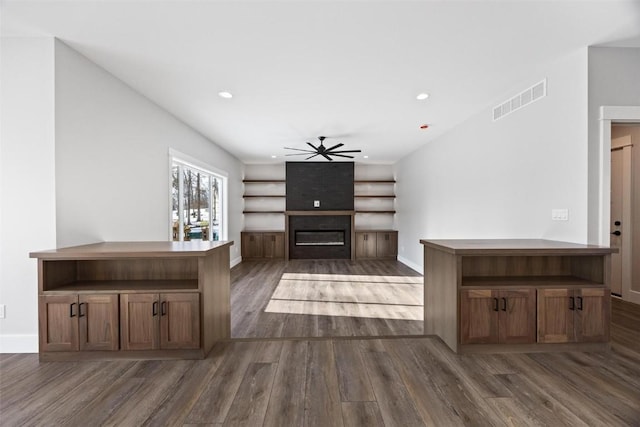 unfurnished living room featuring dark wood-type flooring and ceiling fan