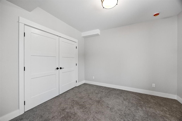 unfurnished bedroom featuring dark colored carpet and a closet