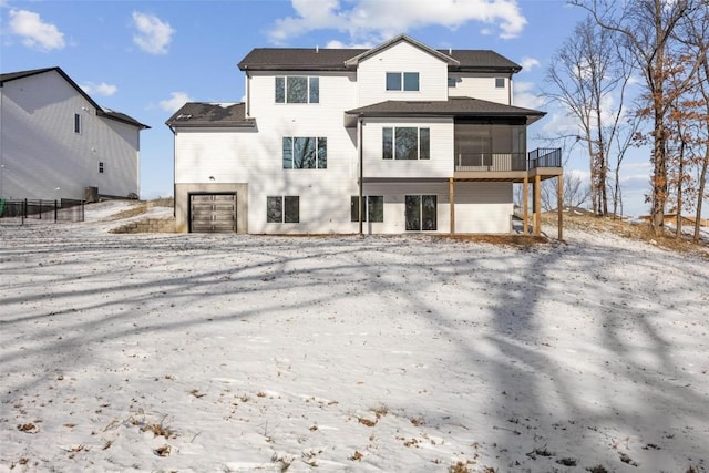 snow covered house featuring a sunroom and a garage