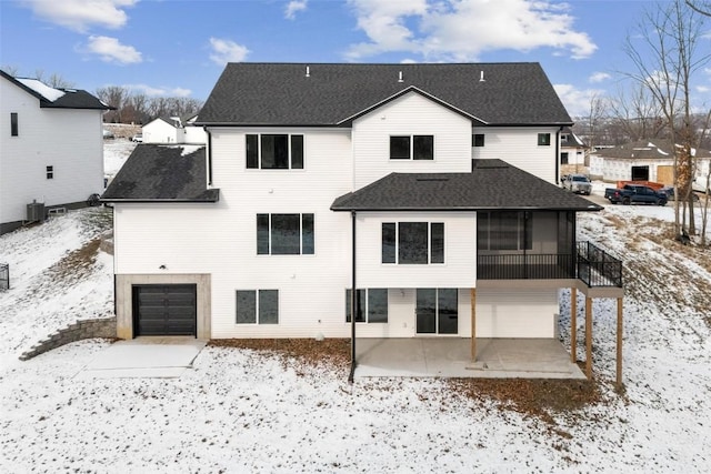 snow covered back of property with a garage