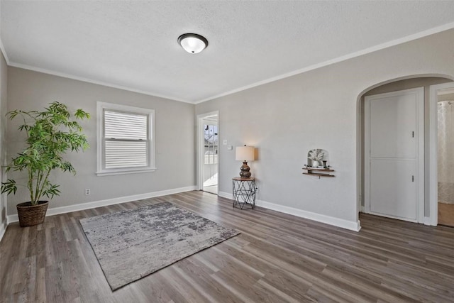 interior space with a textured ceiling, ornamental molding, and dark hardwood / wood-style floors