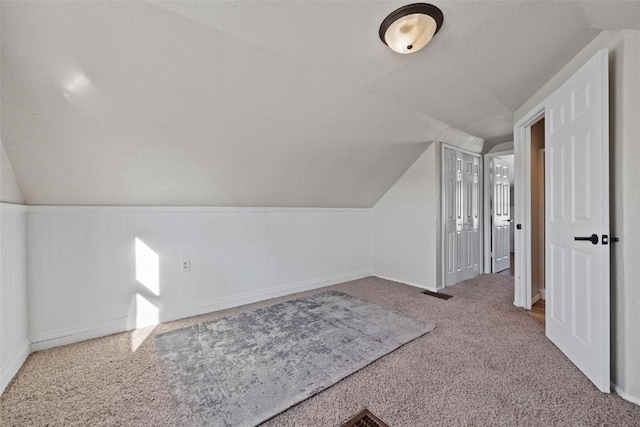 bonus room featuring a textured ceiling, carpet, and lofted ceiling