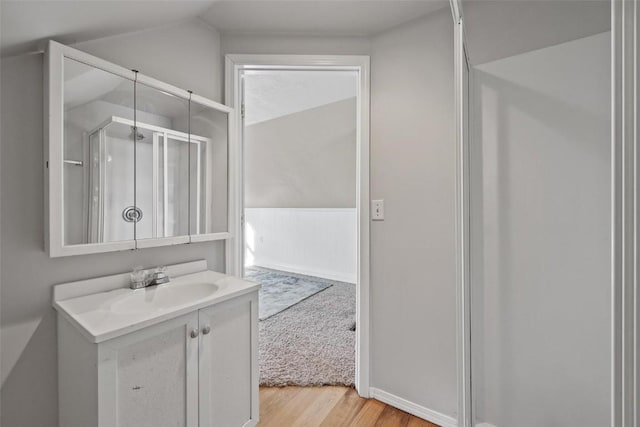 bathroom featuring a shower with door, vaulted ceiling, wood-type flooring, and vanity