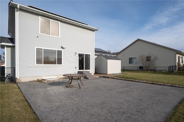 rear view of property featuring a lawn, a patio area, and a storage shed