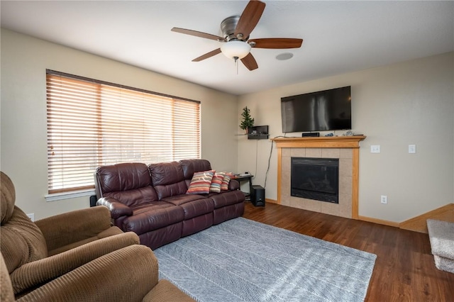 living room featuring dark wood-type flooring, a tiled fireplace, and ceiling fan