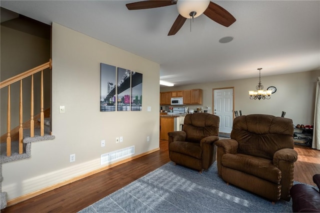 living room featuring ceiling fan with notable chandelier and dark hardwood / wood-style floors