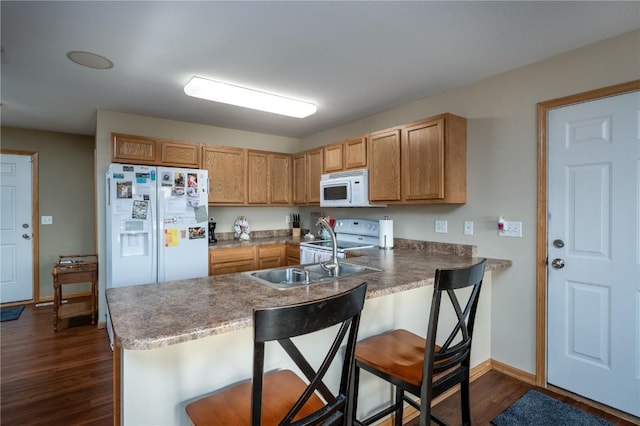 kitchen with white appliances, a kitchen breakfast bar, kitchen peninsula, dark hardwood / wood-style floors, and sink