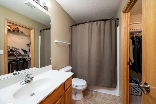 bathroom featuring a textured ceiling, walk in shower, vanity, and toilet