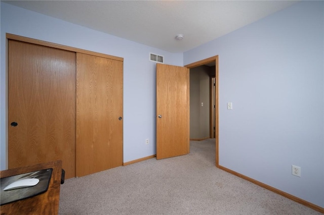 unfurnished bedroom with light colored carpet and a closet