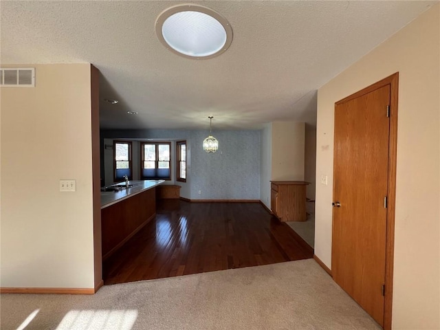 interior space with a textured ceiling, carpet, and a notable chandelier