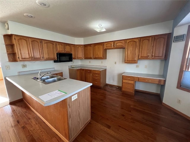 kitchen with sink, dark wood-type flooring, a breakfast bar area, and kitchen peninsula