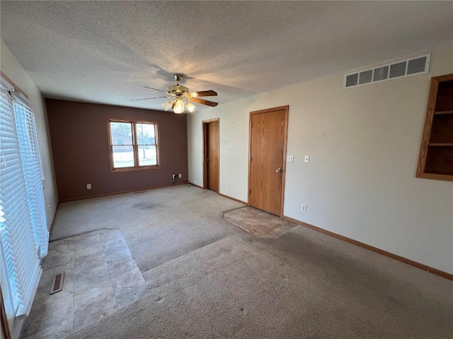 empty room featuring a textured ceiling, ceiling fan, and light carpet