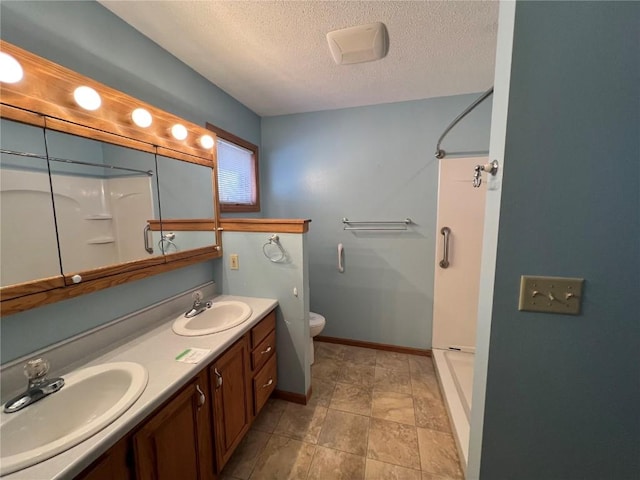 bathroom featuring a textured ceiling, vanity, a shower, and toilet