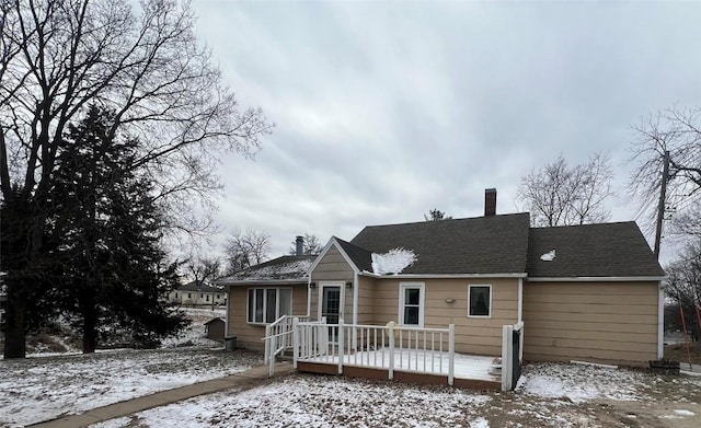 snow covered back of property featuring a wooden deck