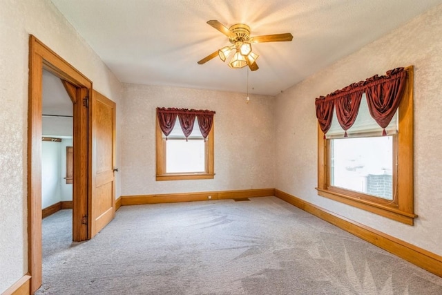 empty room with light carpet, ceiling fan, and a wealth of natural light