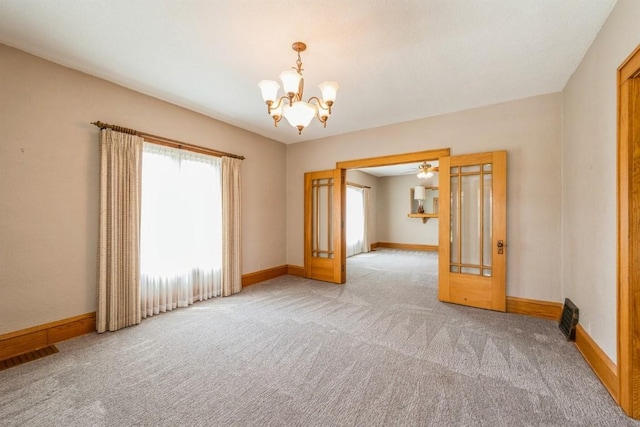 carpeted empty room featuring french doors and a notable chandelier