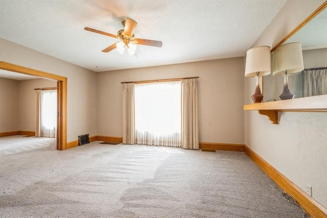 empty room with ceiling fan, light carpet, and a textured ceiling