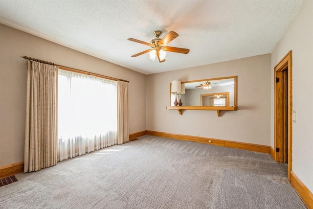 spare room with a textured ceiling, ceiling fan, and carpet floors