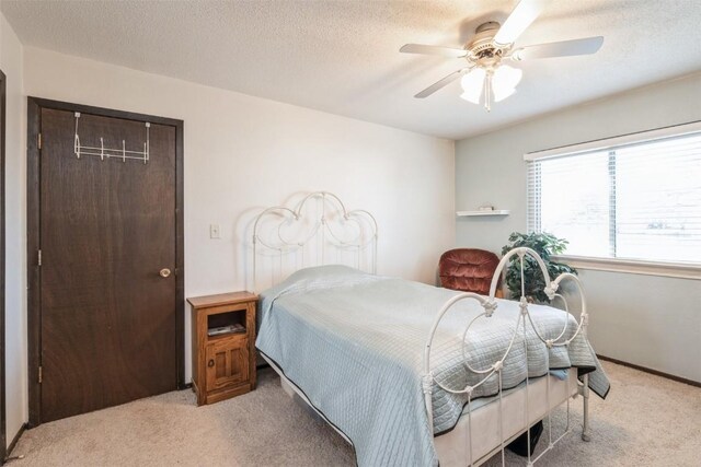 carpeted bedroom with a textured ceiling, ceiling fan, and a closet