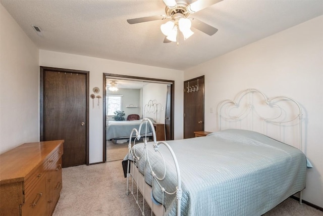 carpeted bedroom featuring a textured ceiling, ceiling fan, and multiple closets