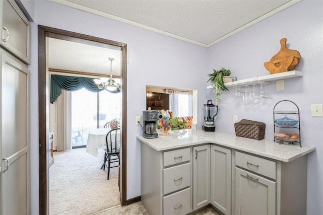 kitchen featuring light stone counters, a notable chandelier, gray cabinetry, and light colored carpet