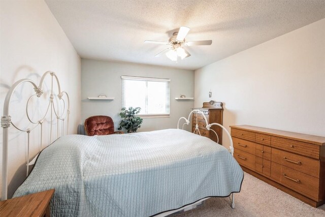 bedroom with a textured ceiling, light colored carpet, and ceiling fan