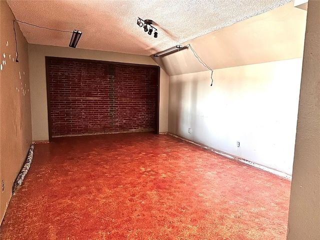 145 Fairway Dr, Lisbon, IA 52253 - unfurnished room with brick wall, a textured ceiling, and lofted ceiling