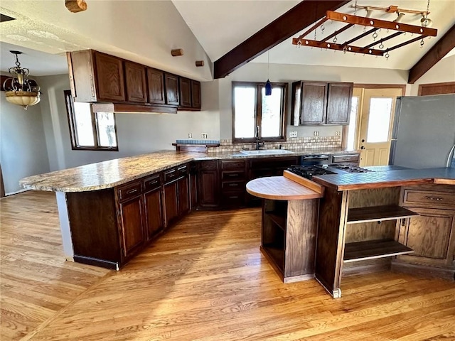 kitchen with sink, light hardwood / wood-style floors, kitchen peninsula, stainless steel refrigerator, and dark brown cabinetry