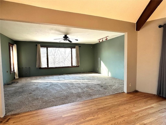 unfurnished room featuring light hardwood / wood-style floors, ceiling fan, track lighting, and beamed ceiling