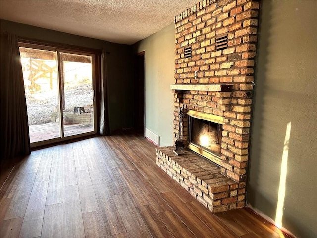 unfurnished living room featuring a fireplace, a textured ceiling, and dark hardwood / wood-style flooring