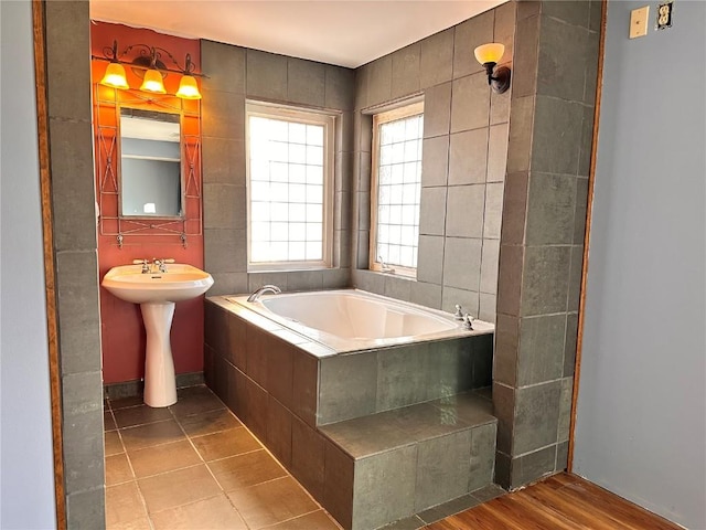 bathroom featuring a relaxing tiled tub, tile patterned floors, and sink