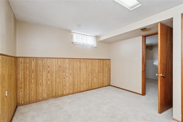 basement with a textured ceiling, wooden walls, and light carpet