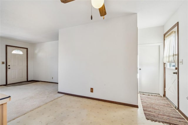 foyer entrance with ceiling fan and light colored carpet