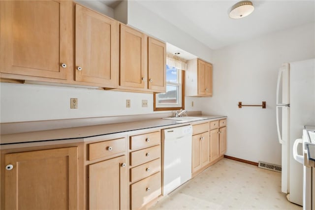 kitchen with white appliances, light brown cabinets, and sink