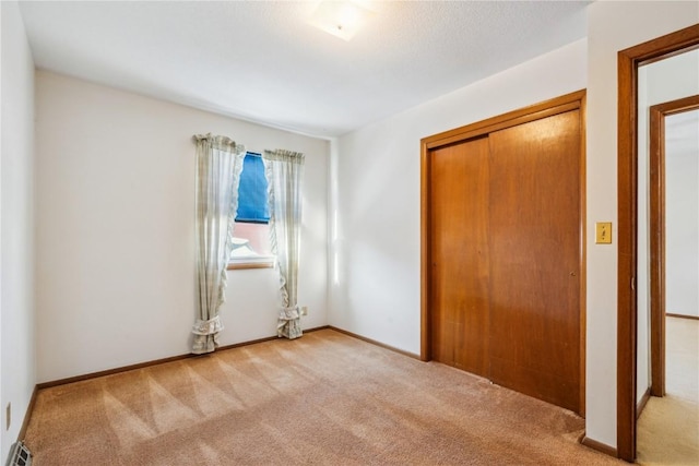 unfurnished bedroom with light colored carpet and a closet