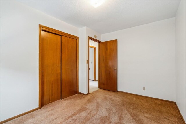 unfurnished bedroom featuring light colored carpet and a closet