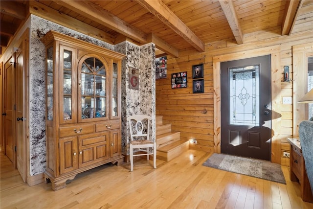 entrance foyer with beam ceiling, wooden ceiling, light hardwood / wood-style floors, and wood walls