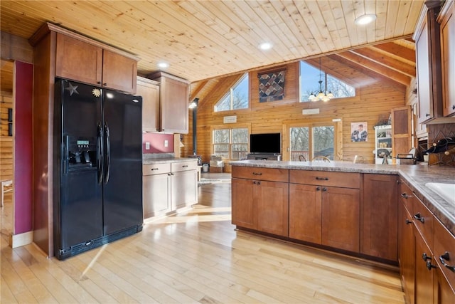 kitchen with black fridge, wooden walls, high vaulted ceiling, and wood ceiling