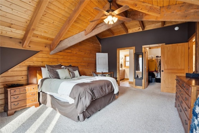 bedroom featuring connected bathroom, wooden walls, beamed ceiling, a spacious closet, and wood ceiling