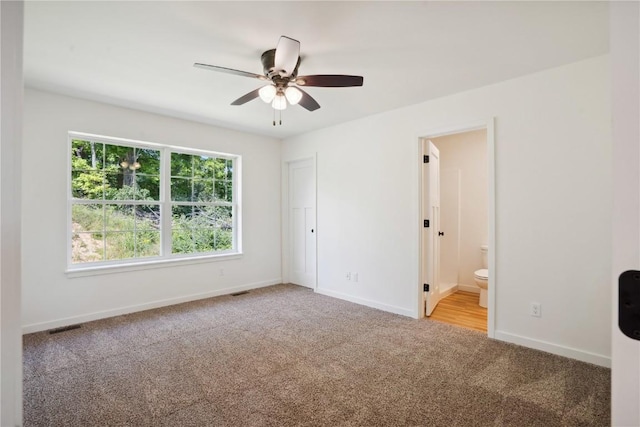 unfurnished bedroom featuring ensuite bath, carpet floors, and ceiling fan