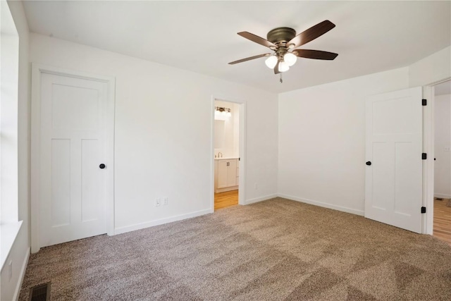 unfurnished bedroom with ensuite bathroom, carpet flooring, and ceiling fan