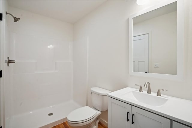 bathroom featuring toilet, a shower, wood-type flooring, and vanity