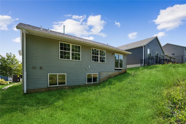 back of house with central AC and a lawn