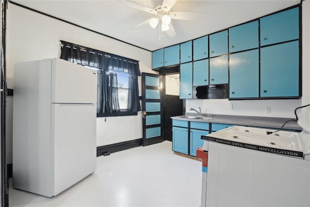 kitchen featuring sink, blue cabinets, ceiling fan, and white fridge