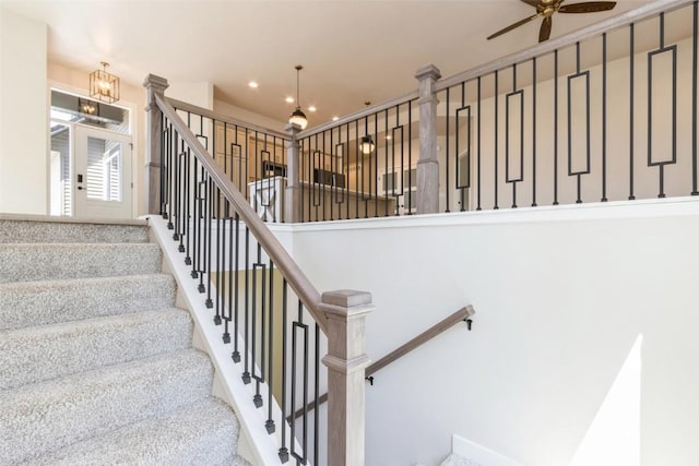 staircase with ceiling fan with notable chandelier